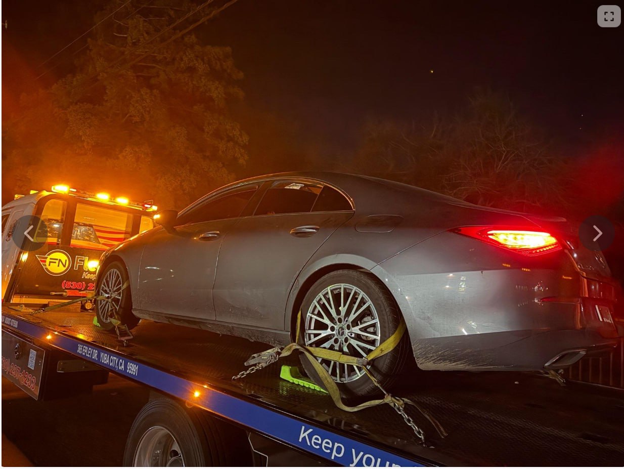 Sedan secured on a flatbed during nighttime light-duty towing response
